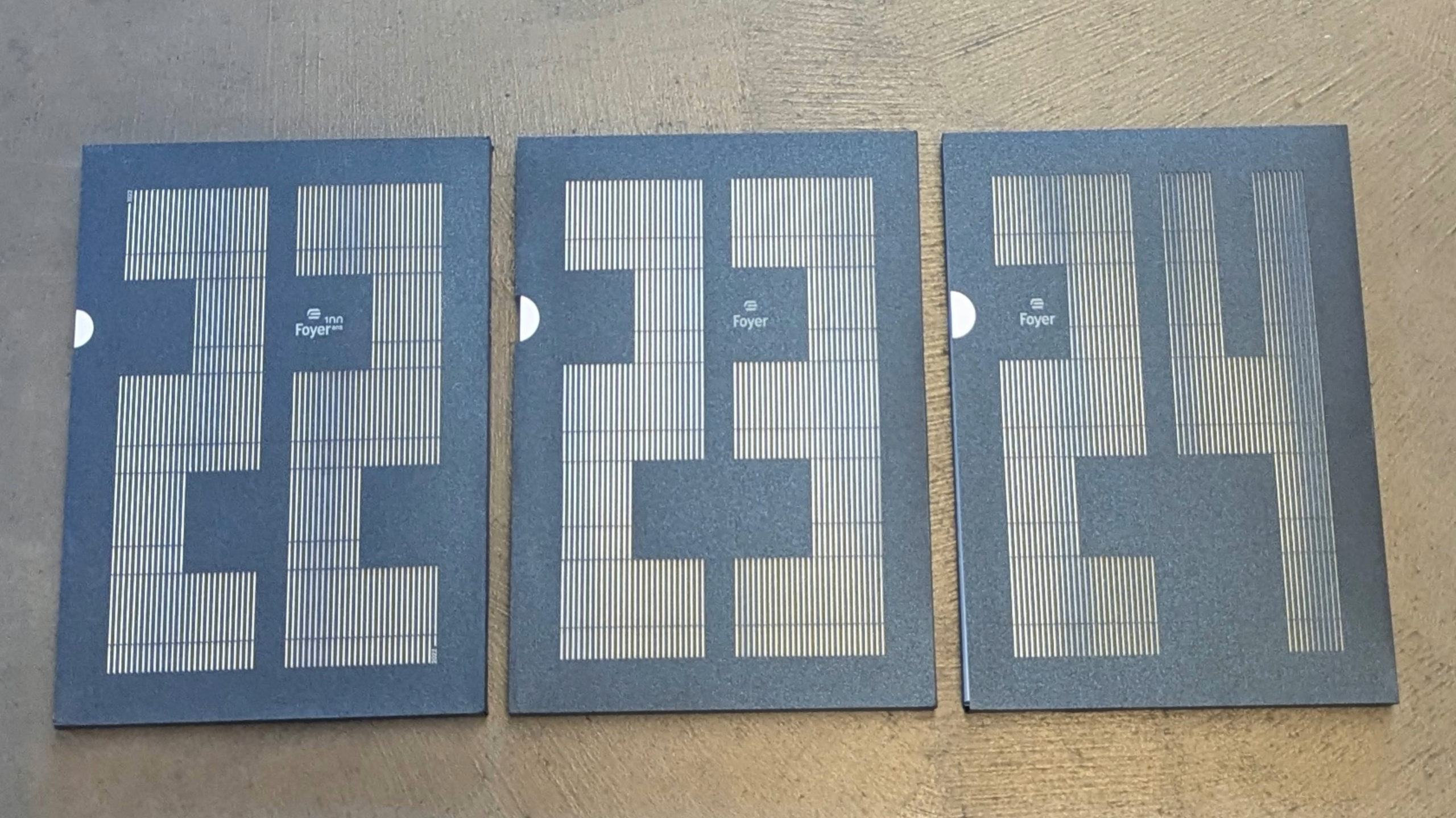 Rapports annuels Foyer 2022-2023-2024, posés, couvertures face objectif, sur un arrière plan gris.