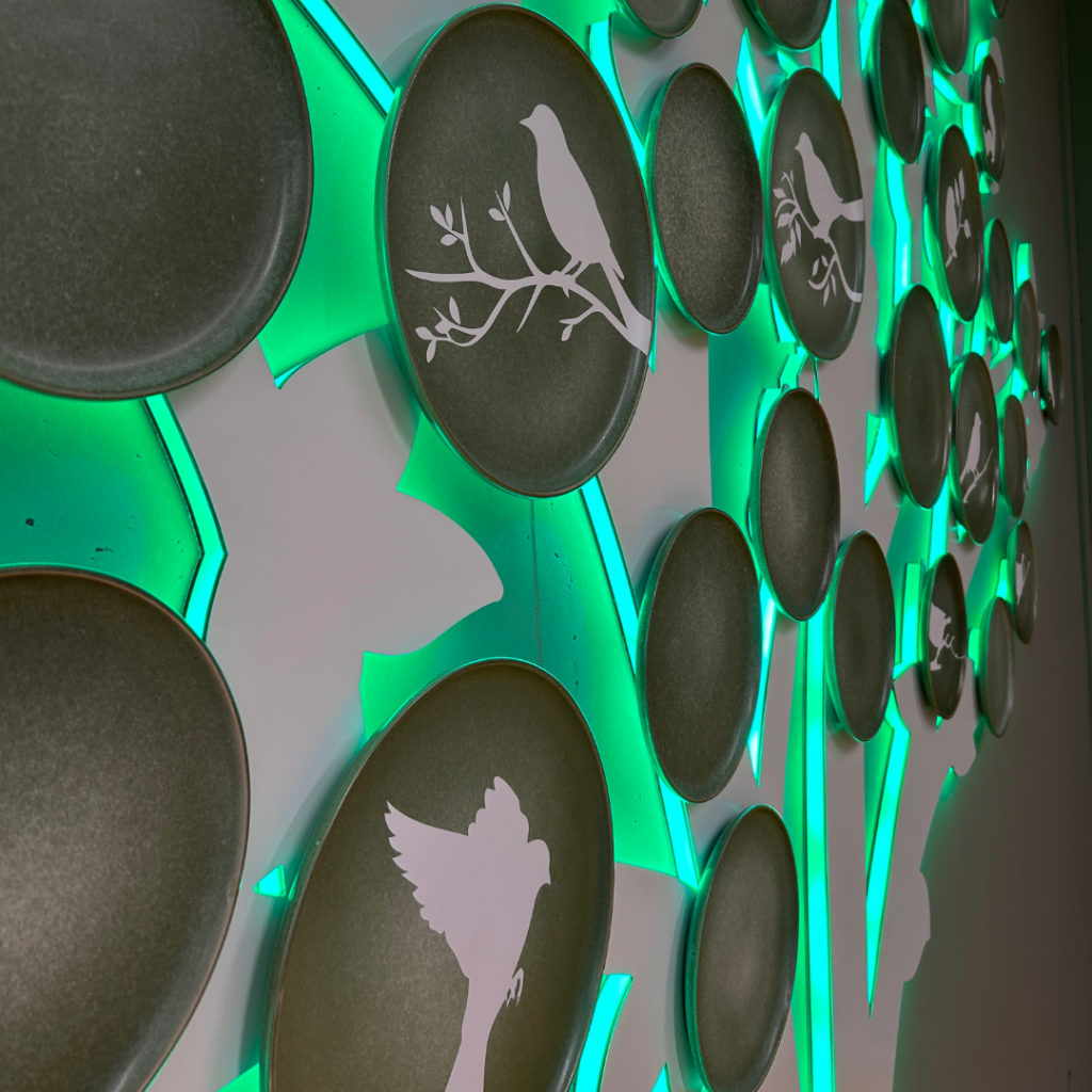 Détail de la décoration murale en forme d’arbre avec disques noirs ornés de silhouettes blanches d’oiseaux et de branches.