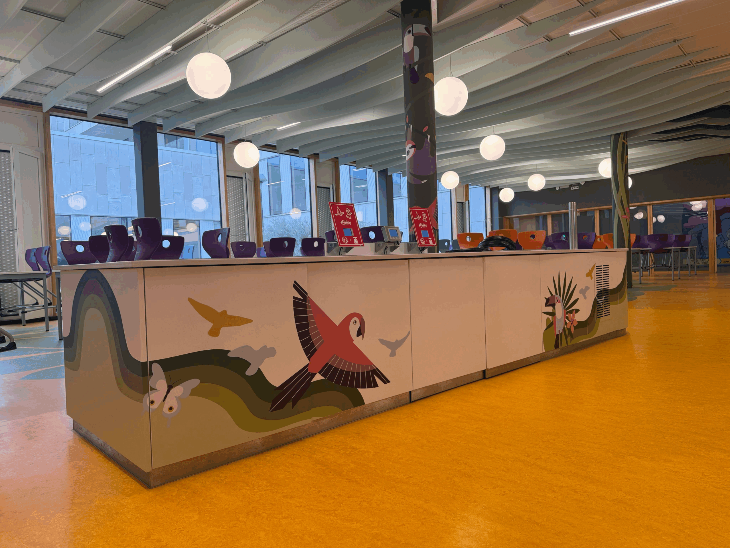 Comptoir blanc décoré d’oiseaux colorés dans un espace convivial.