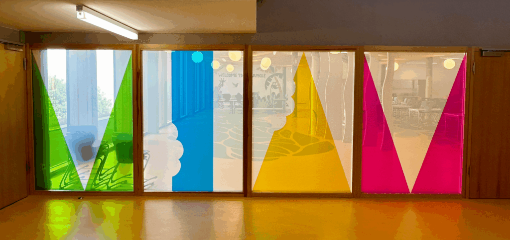 Baies vitrées décorées de filtres colorés verts, bleus, jaunes et roses en formes géométriques translucides.