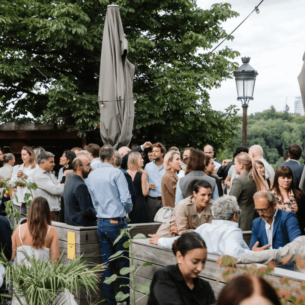 Foule des invités à la soirée de lancement en extérieur qui échangent.