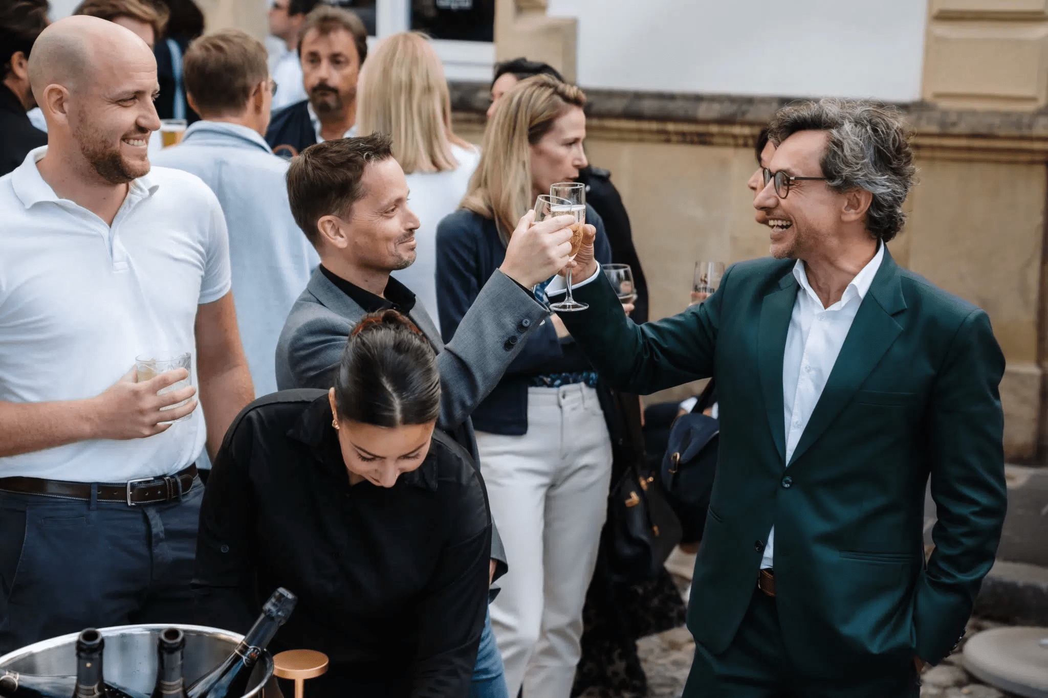 2 personnes qui trinquent, avec foule de personnes autour d'eux.
