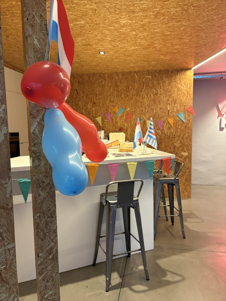 Comptoir décoré pour fête : fanions multicolores, ballons rouge et bleu, drapeaux luxembourgeois