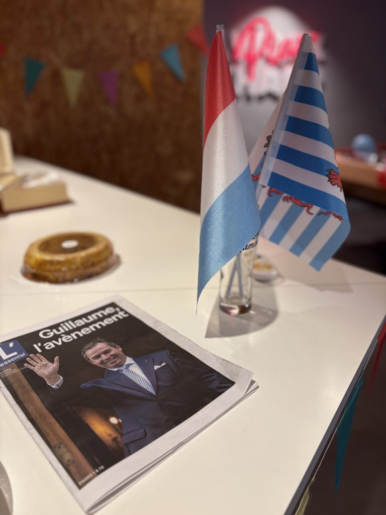 Deux petits drapeaux sur comptoir, une du journal L’Essentiel titrant « Guillaume, l’avènement