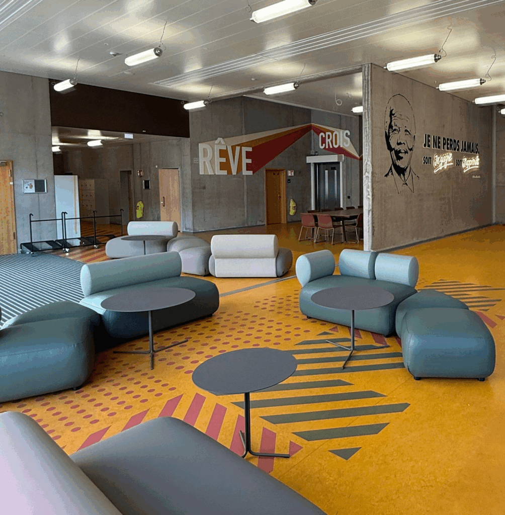 Espace de collaboration moderne avec mobilier design et signalétique murale inspirante dans les tons colorés orange et bleus