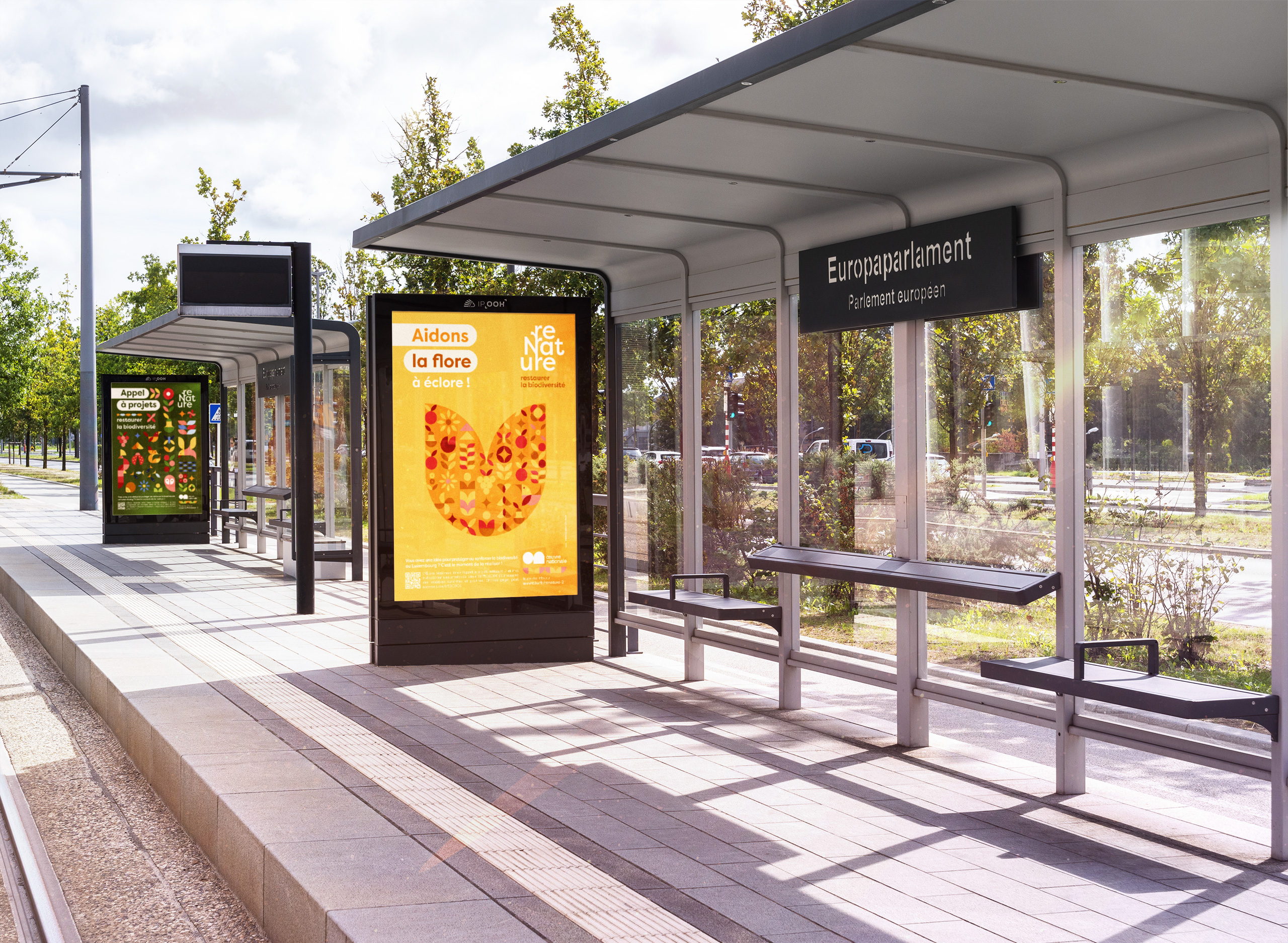 Abribus du quartier du Parlement europeen a Luxembourg avec une grande affiche jaune reNature dediee a la flore et une autre affiche verte plus loin promouvant un appel a projets pour restaurer la biodiversite.