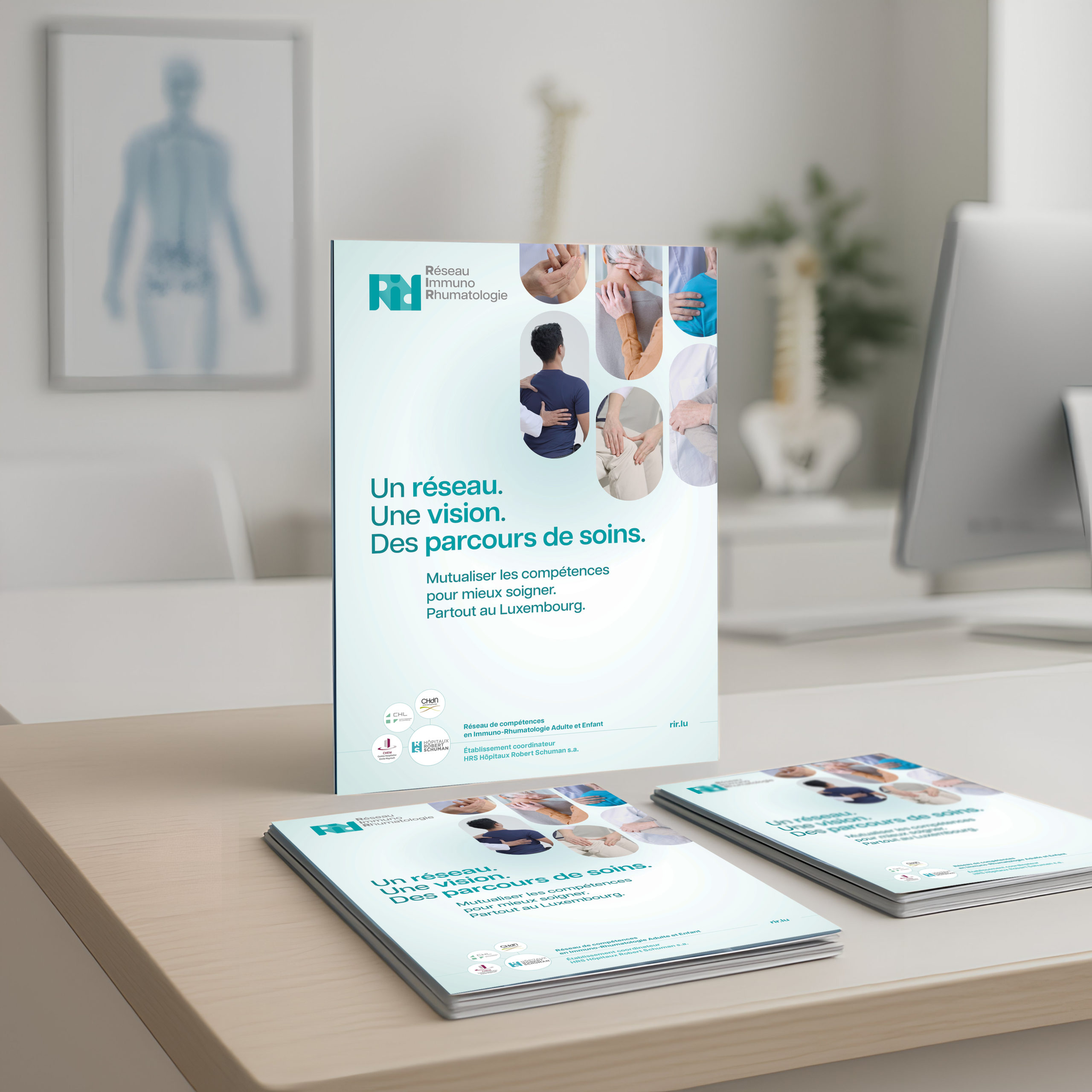 Brochure du Reseau Immuno Rhumatologie posee sur un bureau dans un cabinet medical avec des exemplaires a plat au premier plan et une illustration anatomique flou en arriere plan.