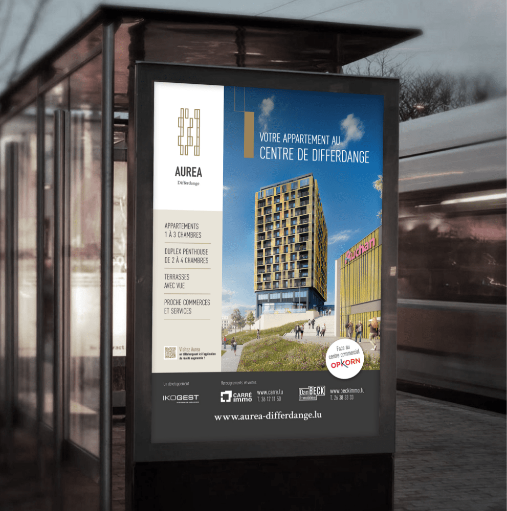 Communication d'un projet immobilier illustrée par une affiche publicitaire Aurea Differdange sur un abribus