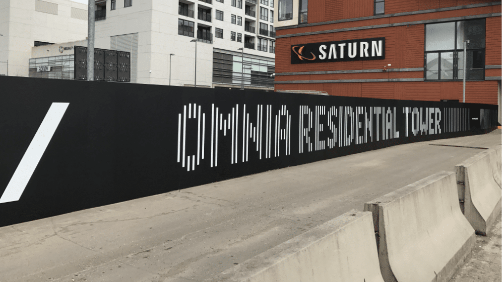 Communication d'un projet immobilier mise en valeur par une palissade noire Omnia Residential Tower dans un quartier urbain
