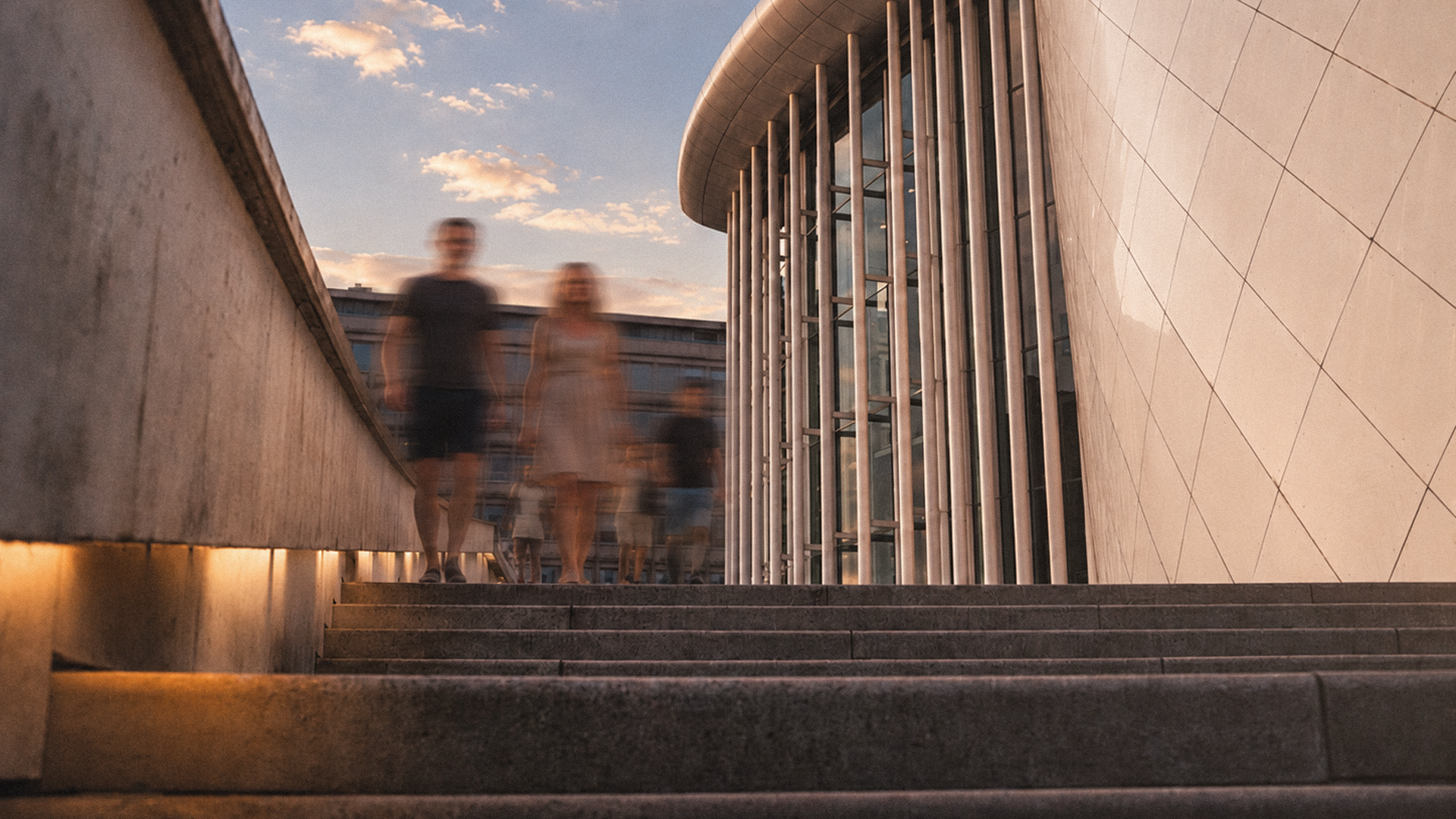 Architecture extérieure de la Philharmonie Luxembourg animée par des spectateurs au crépuscule.