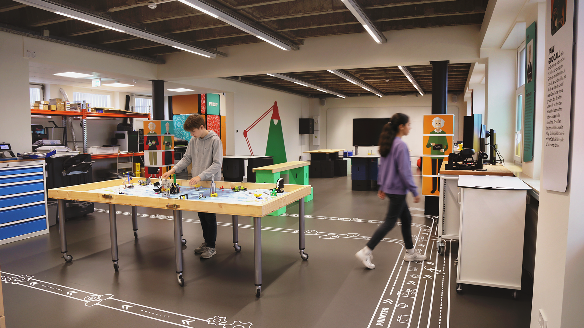 Élèves en activité autour d'une table d'assemblage de robotique dans le Makerspace, un espace éducatif spacieux et équipé.