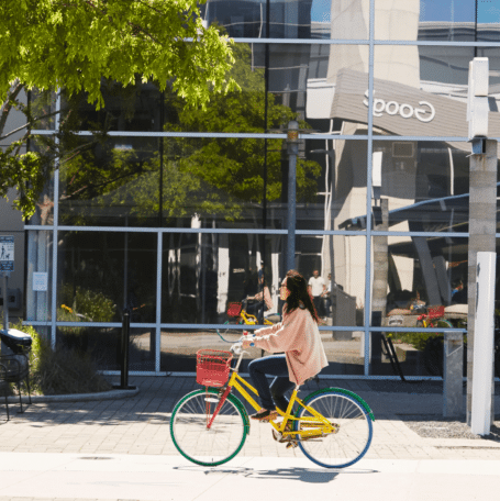 Personne roulant à vélo coloré Google devant les bâtiments du siège de Google.