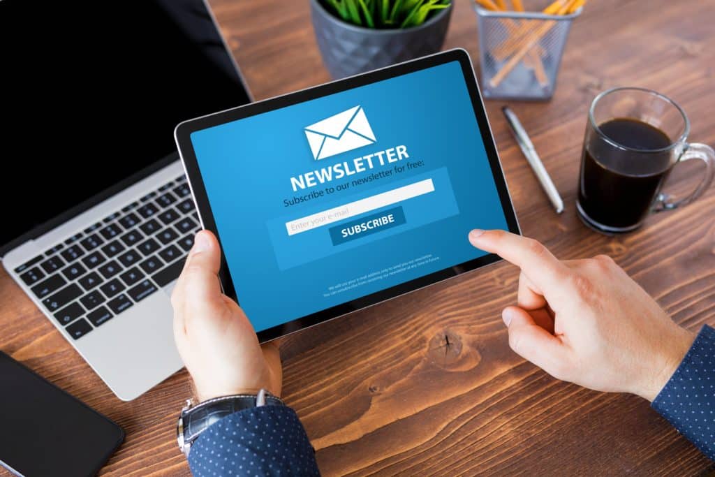 Personne utilisant une tablette pour s’abonner à une newsletter, écran affichant un bouton Subscribe