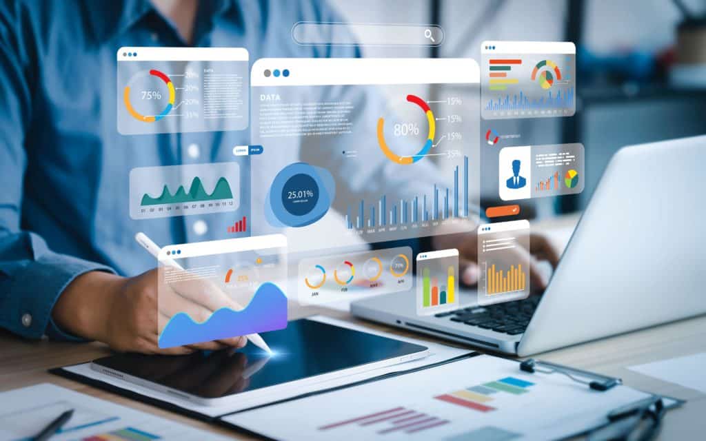 Personne utilisant une tablette et un ordinateur portable avec des graphiques et tableaux de données analytiques en surimpression à l'écran, représentant des statistiques et des visualisations de données numériques.