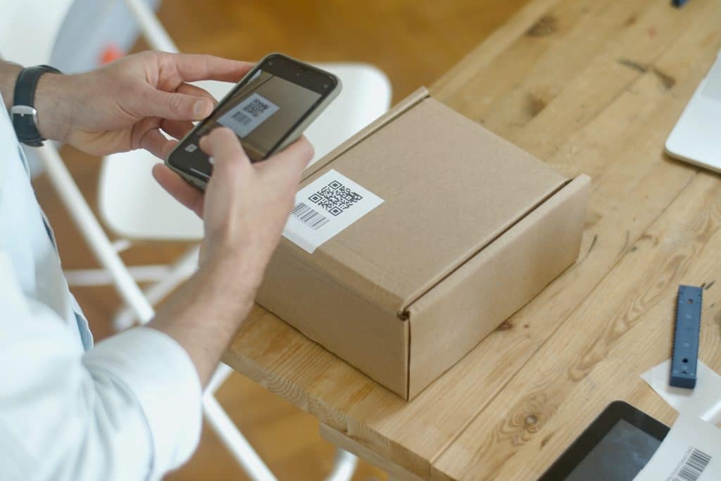Photo représentant une personne prenant en photo un QR code affiché sur un carton.