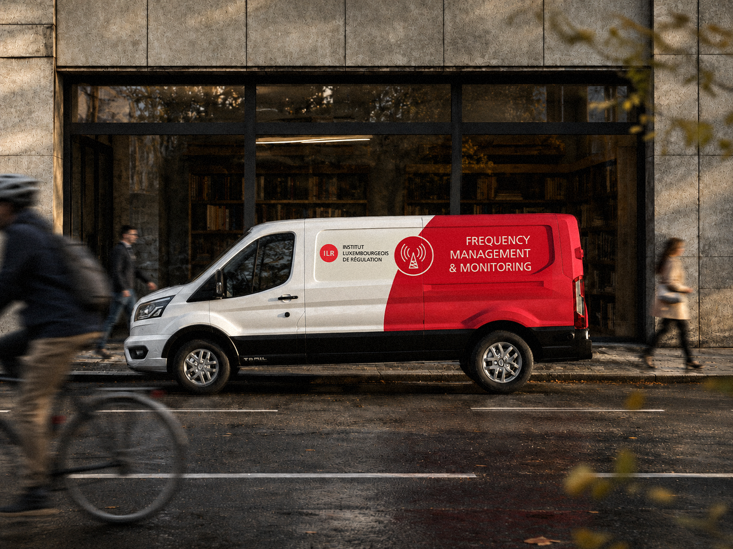 ) Camionnette blanche et rouge de l'ILR stationnée dans une rue.