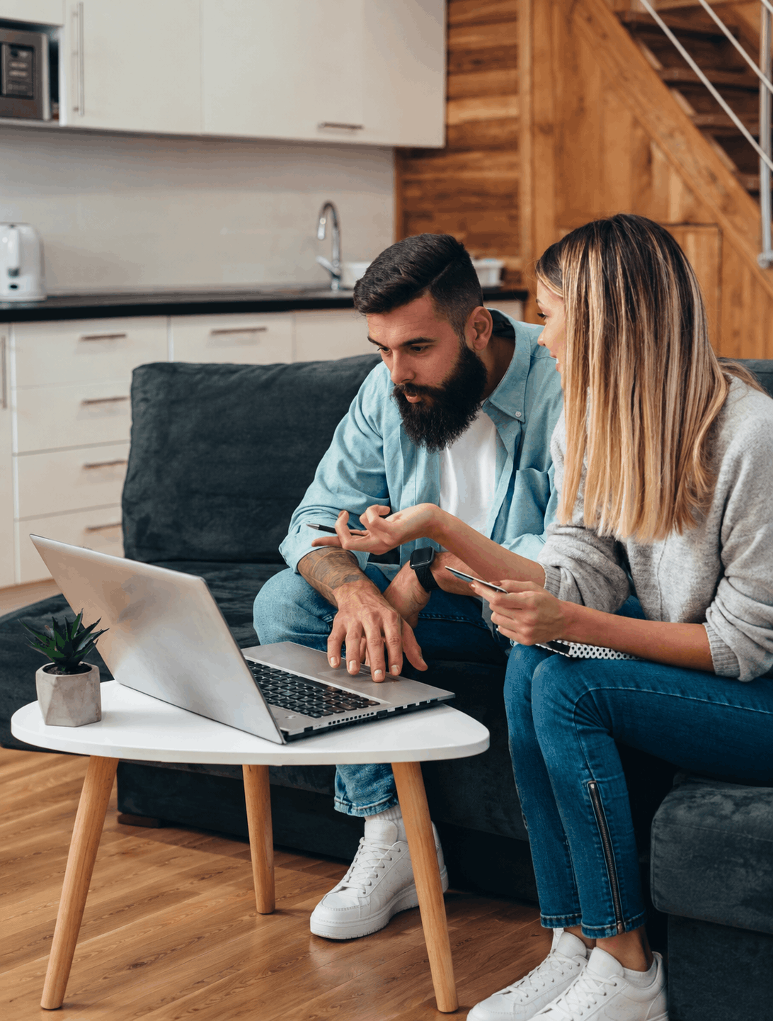 Jeune couple effectuant des démarches ou paiements en ligne sur un ordinateur portable.