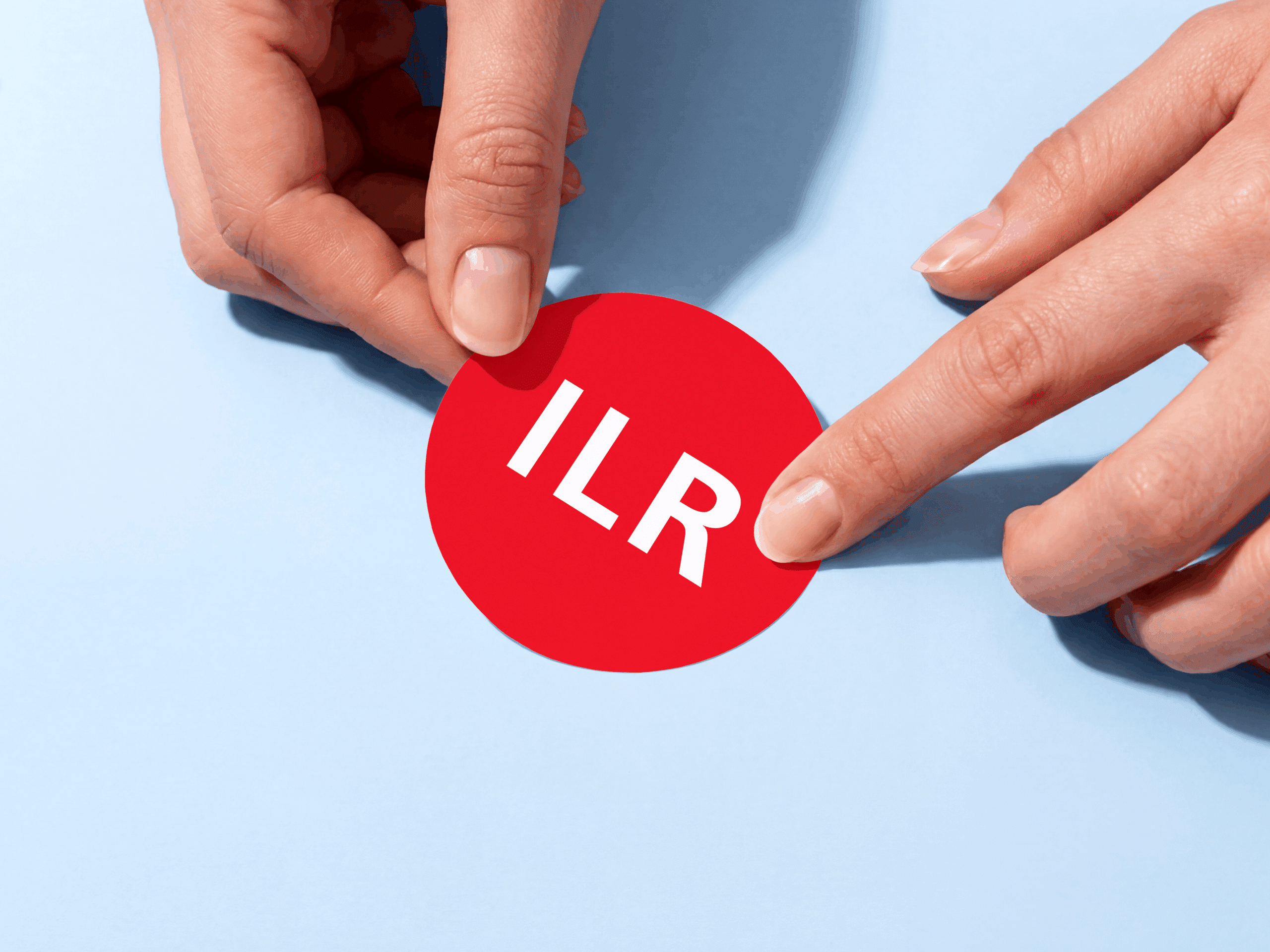 Présentation de l'identité visuelle avec un macaron rouge du logo ILR tenu à deux mains sur fond bleu.
