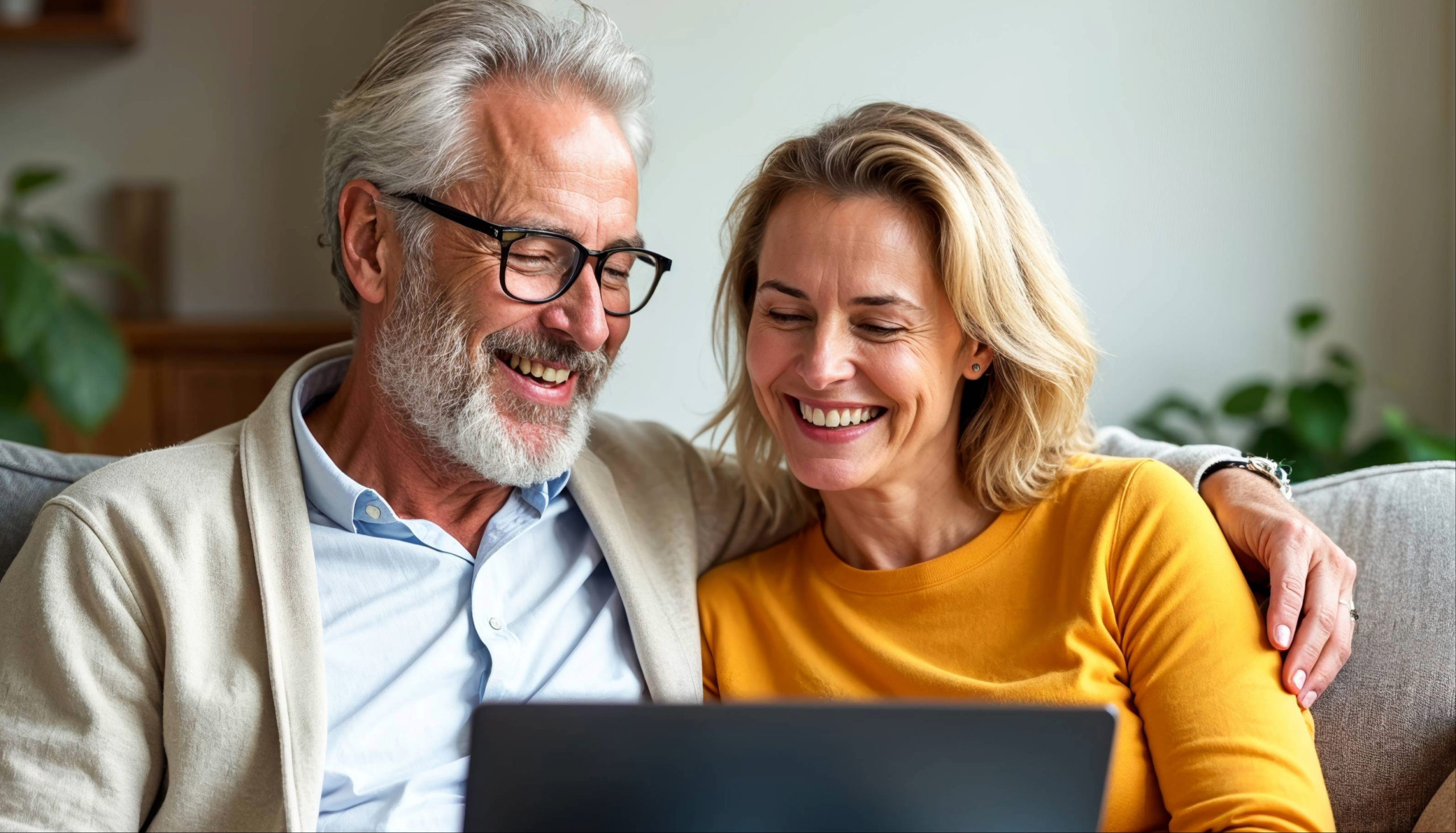 Couple de seniors utilisant une connexion internet sur un ordinateur portable depuis leur salon.