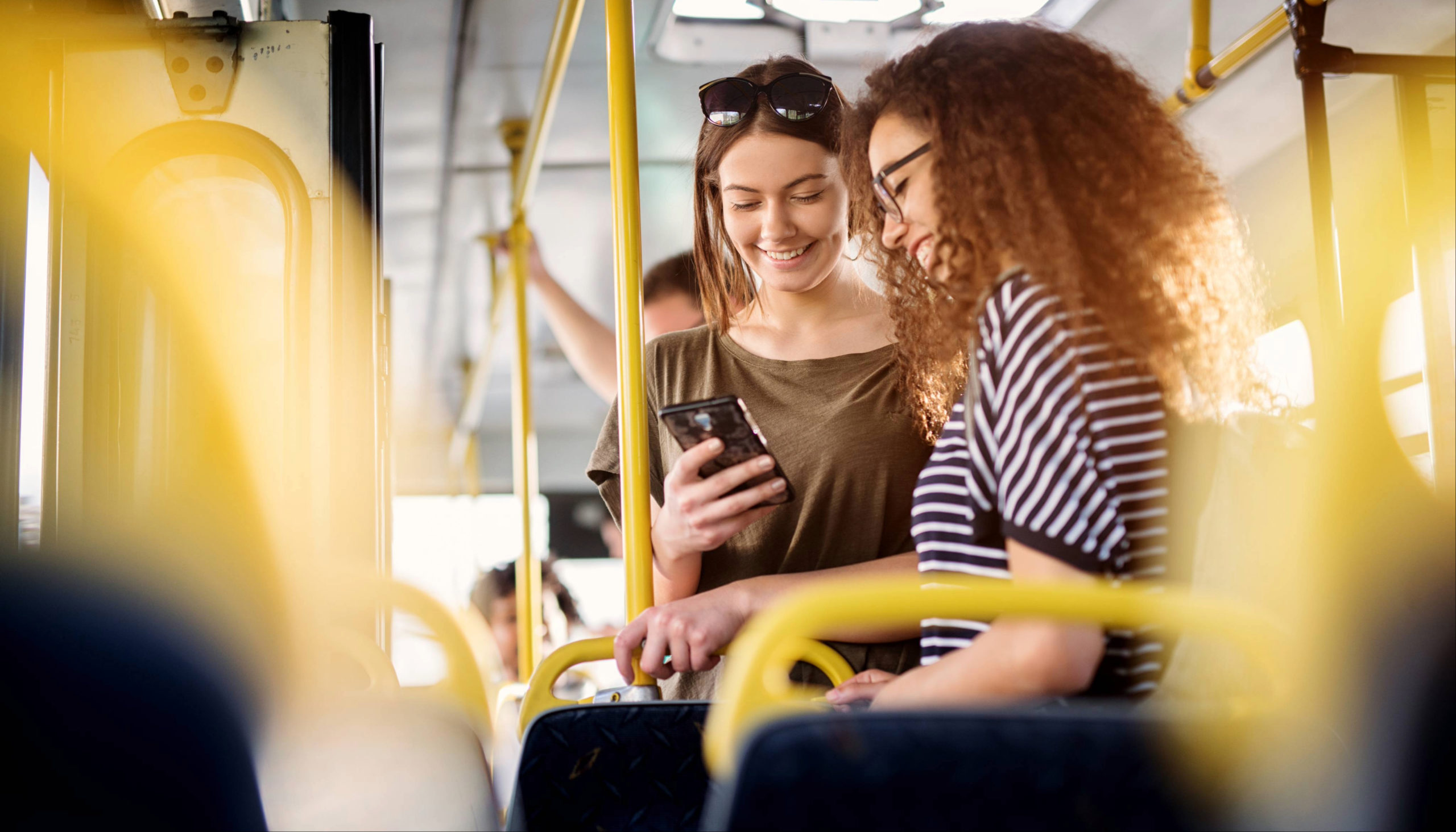 Deux jeunes femmes consultant un smartphone dans les transports en commun, illustrant l'usage de l'internet mobile.