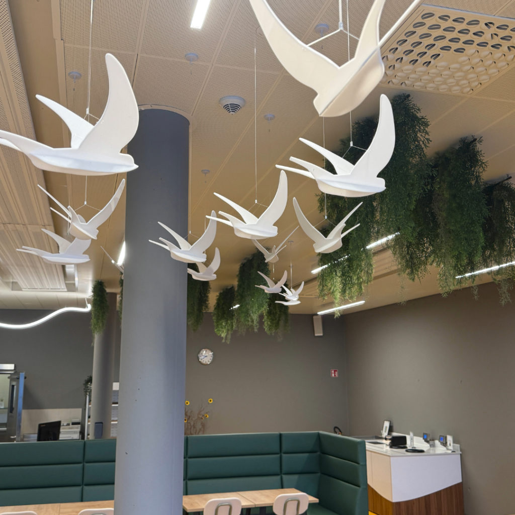 Suspensions décoratives en forme d’oiseaux blancs accrochées au plafond de la cafétéria rénovée.