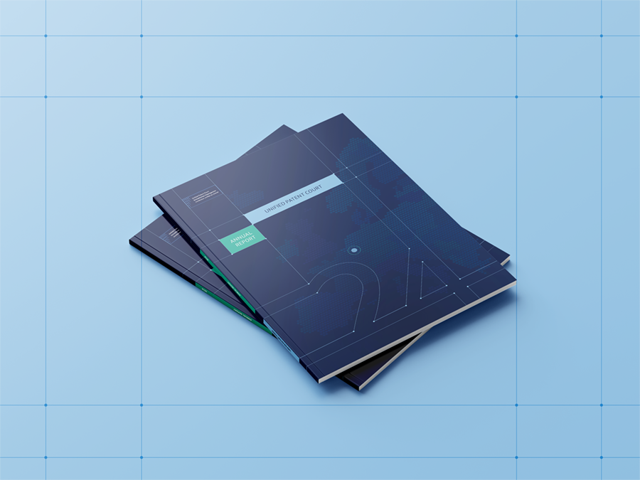 Pile de rapports annuels du Unified Patent Court avec une couverture bleue foncée affichant des éléments graphiques et textuels, posés sur un fond bleu quadrillé.