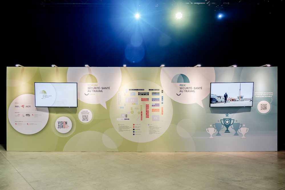 Mur d’exposition du Forum Sécurité-Santé au Travail avec écrans, plans et visuels illustrant les prix et la campagne Vision Zéro