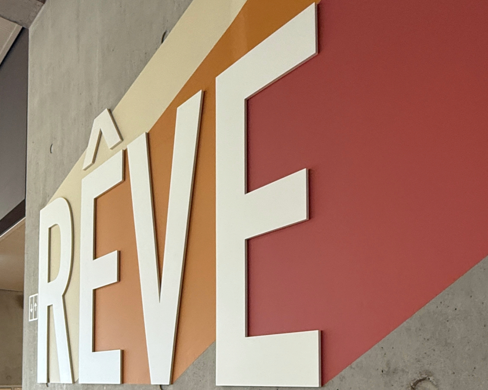 Mot RÊVE en grandes lettres blanches sur fond coloré mural.