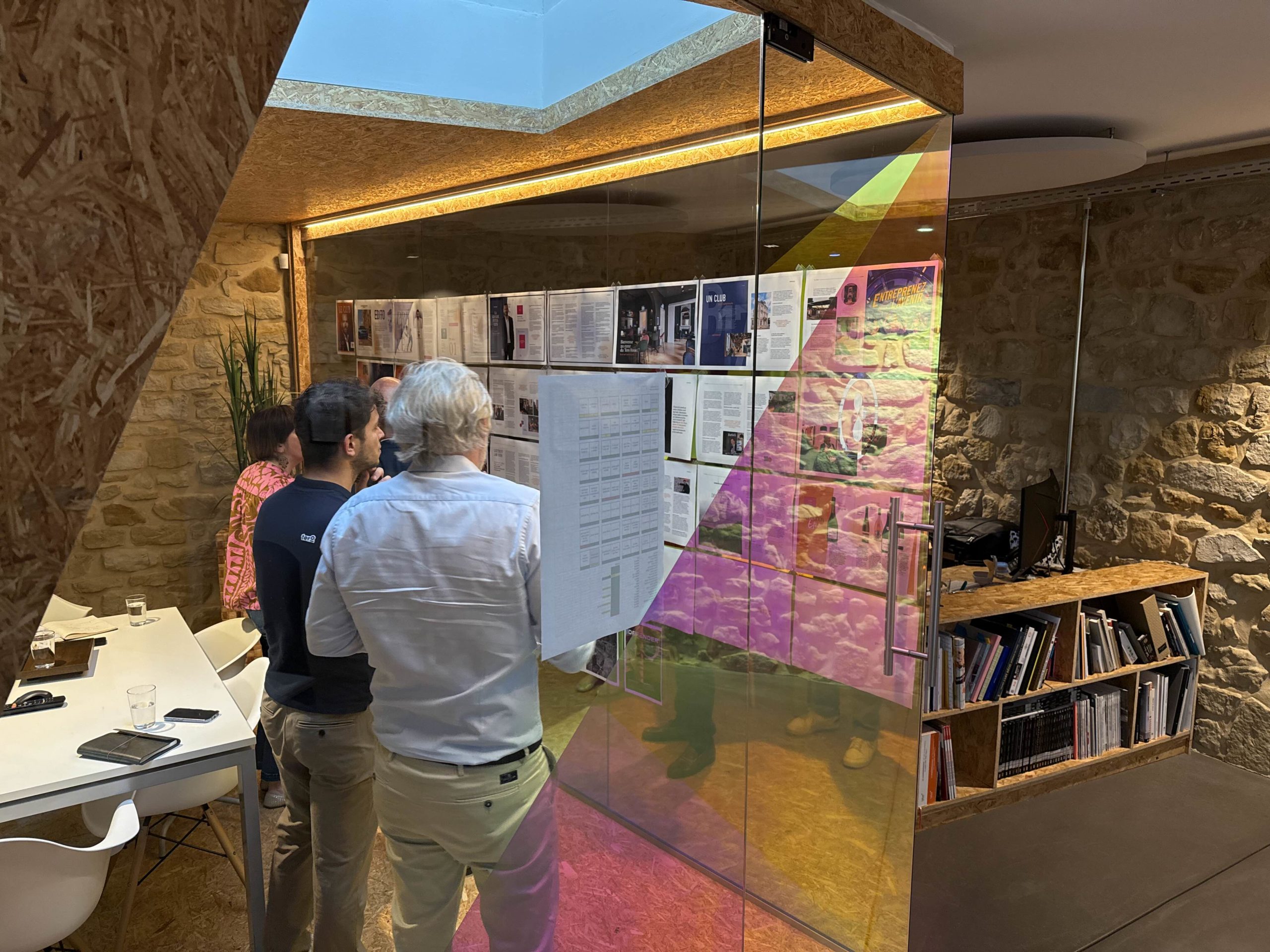 Équipe de travail consultant un chemin de fer éditorial affiché au mur lors d'une réunion collaborative.