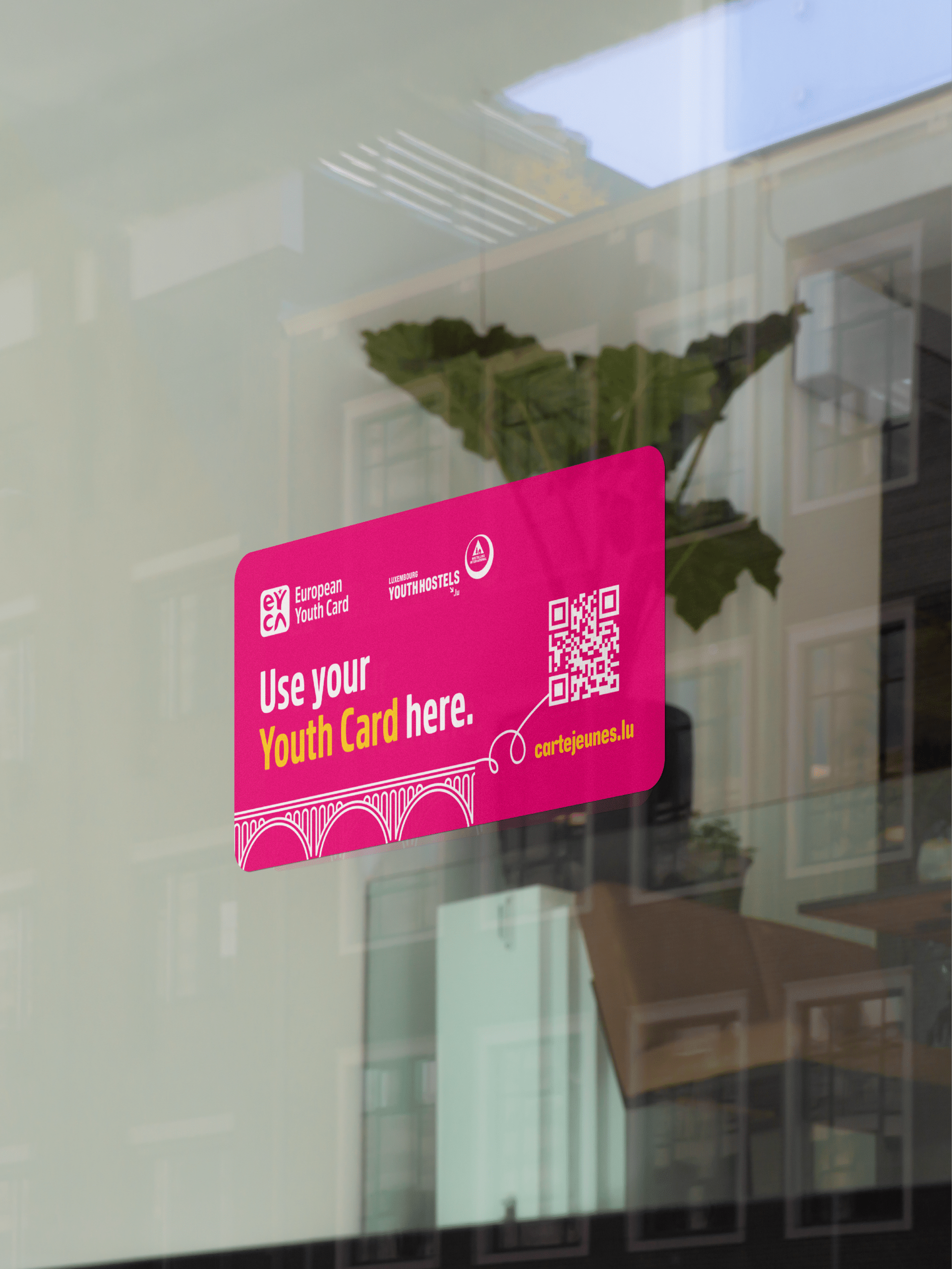 Autocollant rose sur une vitrine affichant "Use your Youth Card here" avec un QR code et le lien cartejeunes.lu.
