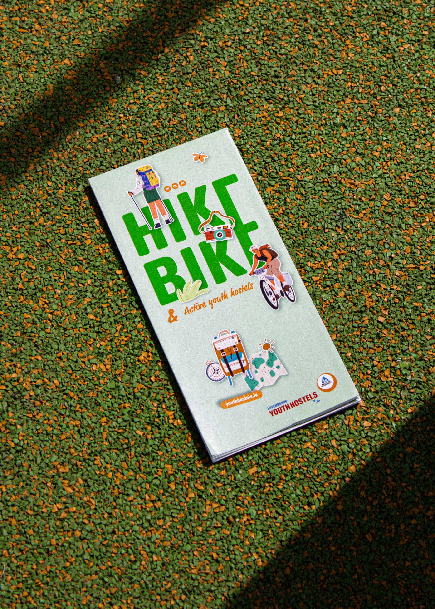 Dépliant vert titré Hike & Bike pour les auberges de jeunesse actives, décoré d'autocollants de randonnée et de vélo.