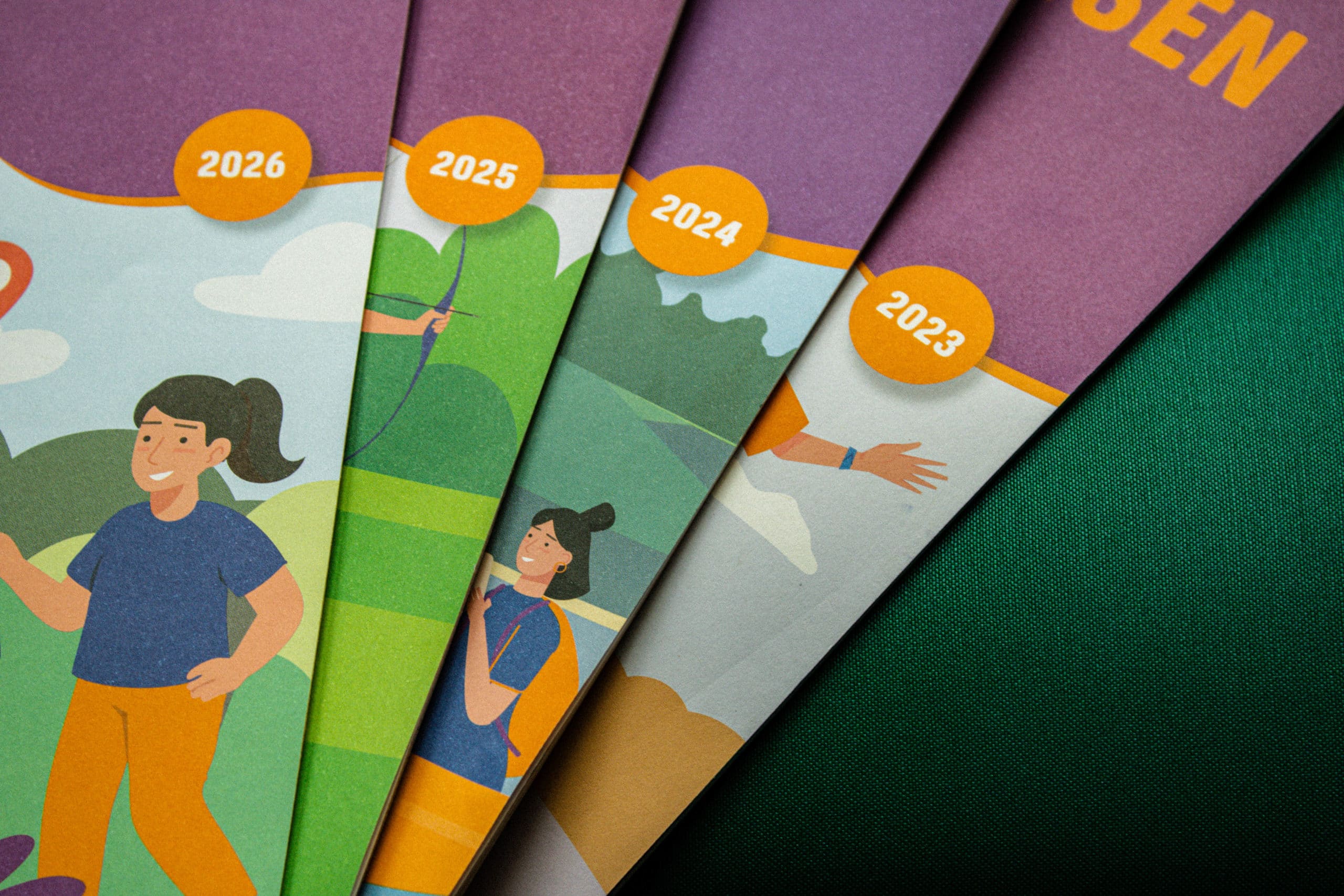 Couvertures de plusieurs brochures empilées, affichant les années 2023 à 2026 avec des illustrations d'activités de plein air.