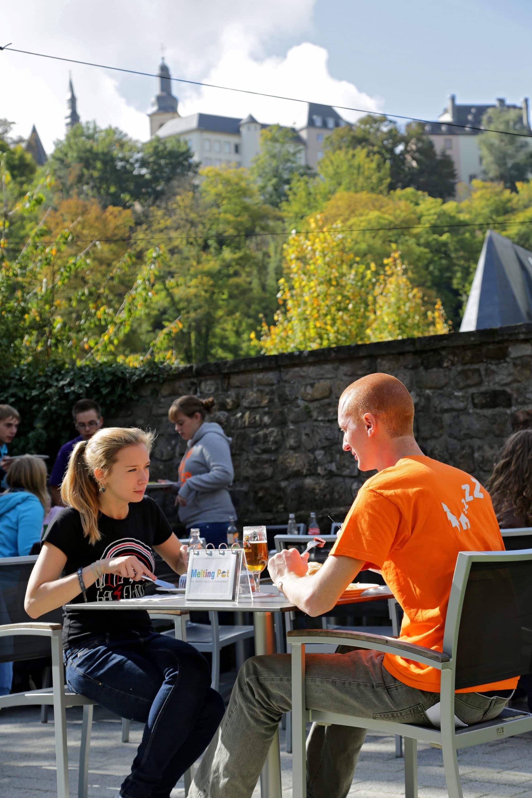 Clients mangeant sur la terrasse extérieure du restaurant Melting Pot avec vue sur les hauteurs du Pfaffenthal.