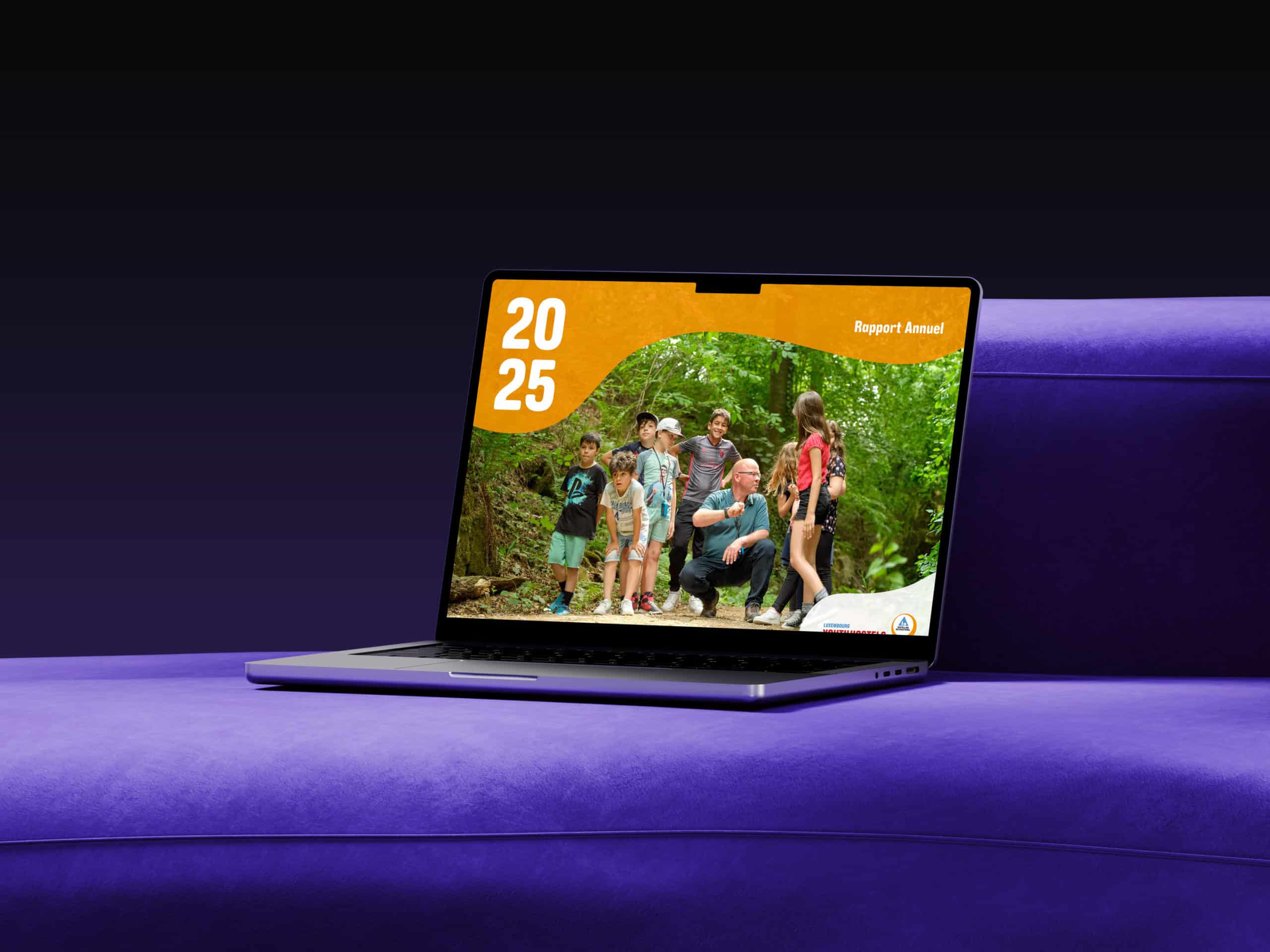 Édition numérique du rapport annuel 2025 de Youth Hostels affichée sur un ordinateur, illustrant un groupe d'enfants en excursion dans la forêt.