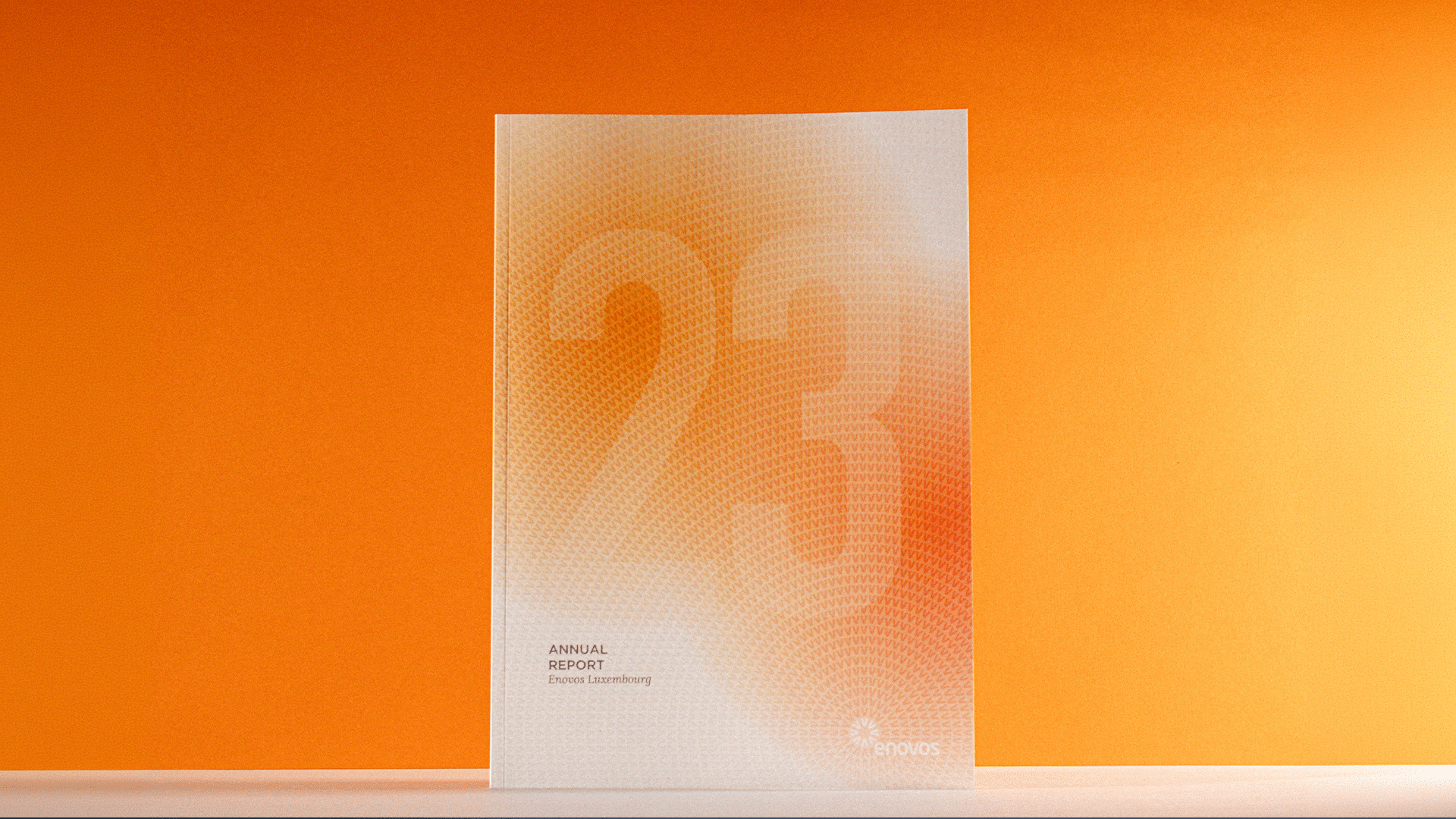 Brochure imprimée du rapport annuel 2023 d'Enovos Luxembourg présentant un design graphique orange.