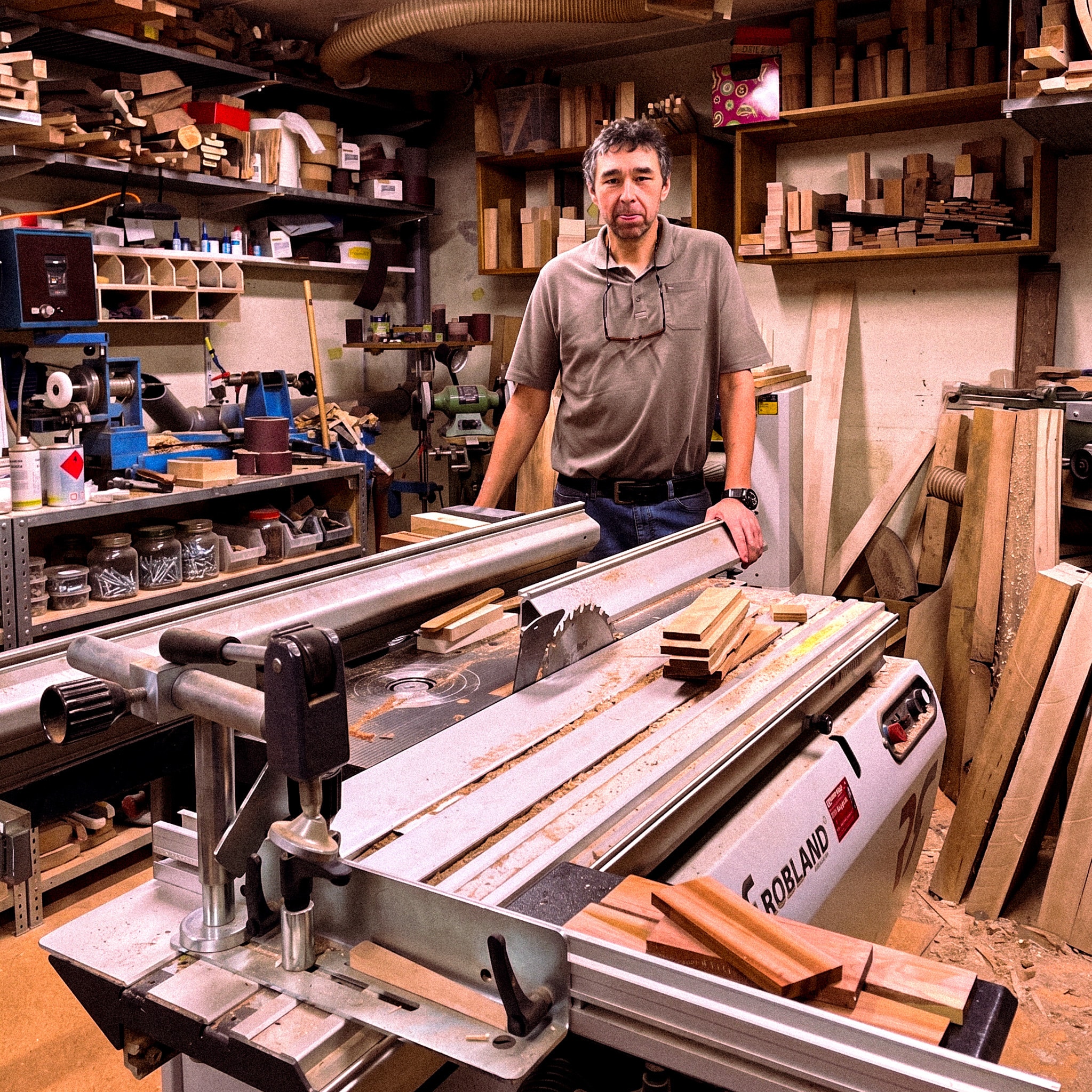 Menuisier posant dans son atelier complet derrière une scie à table professionnelle Robland.