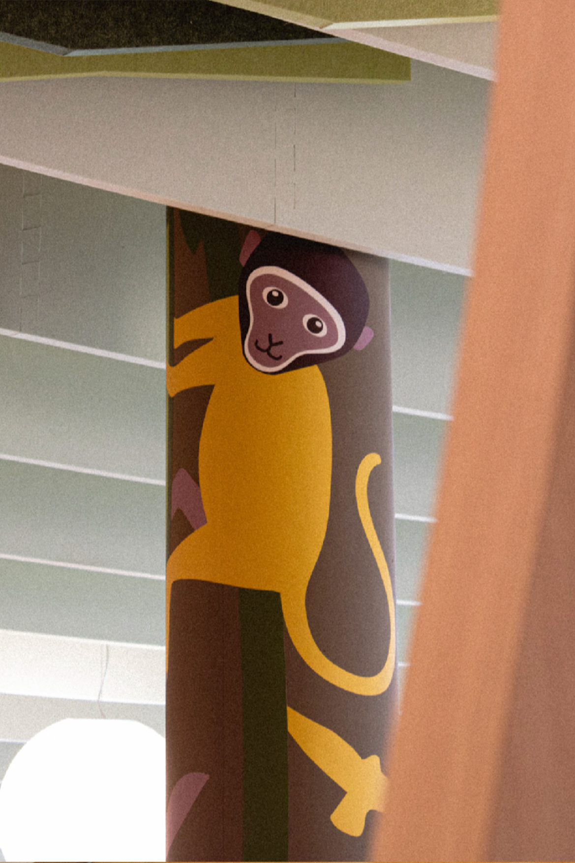Colonne cylindrique habillée d'une illustration de singe jaune grimpant à un tronc d'arbre