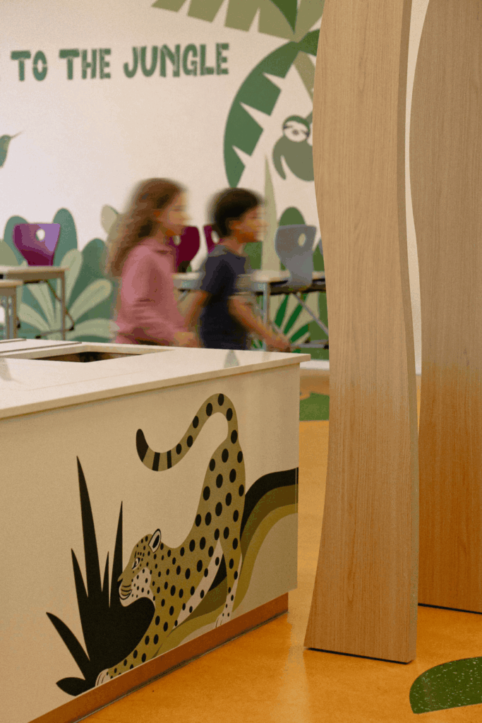 Aménagement sur mesure de la cantine scolaire Vauban avec meuble décoré, pilier en bois façon arbre et fresque jungle