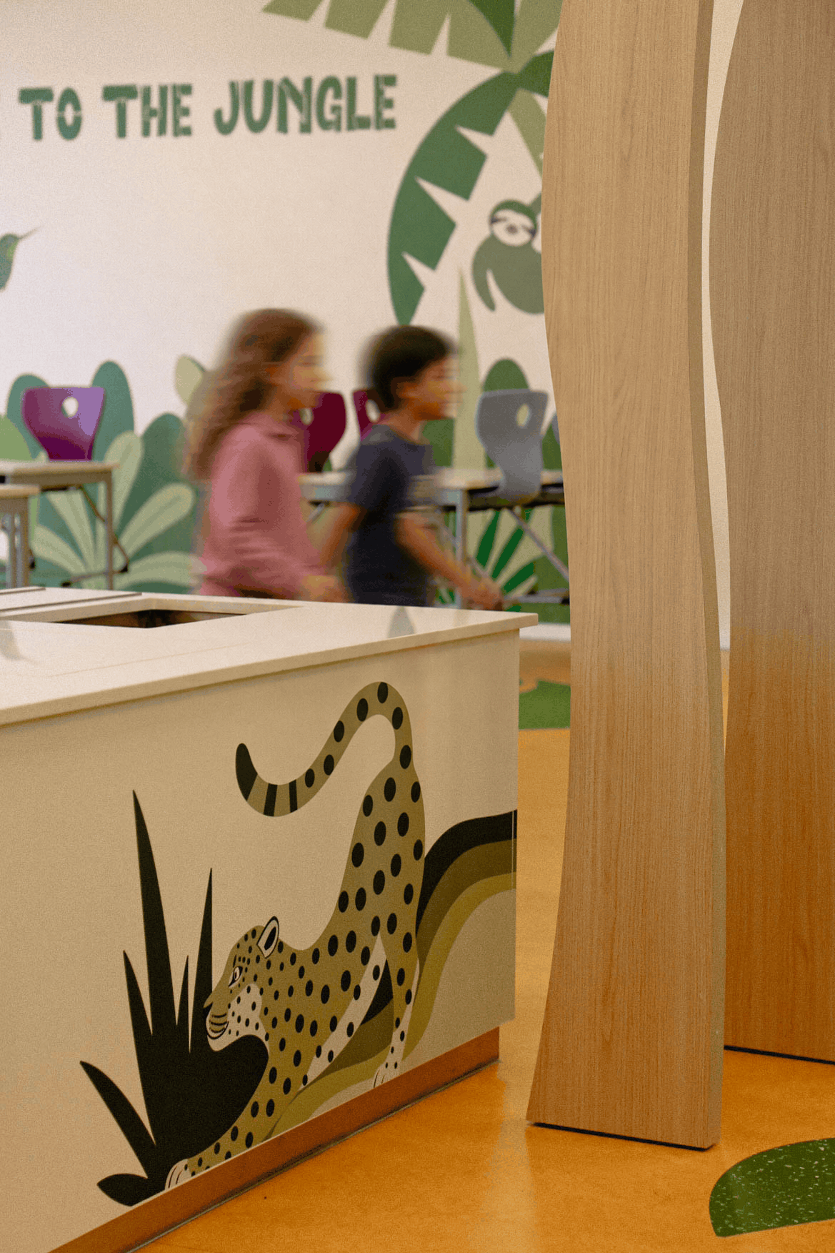 Aménagement sur mesure de la cantine scolaire Vauban avec meuble décoré, pilier en bois façon arbre et fresque jungle
